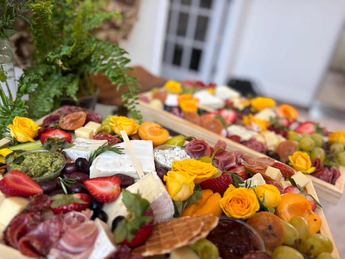 Grazing table styled with yellow roses, cheeses and charcuterie