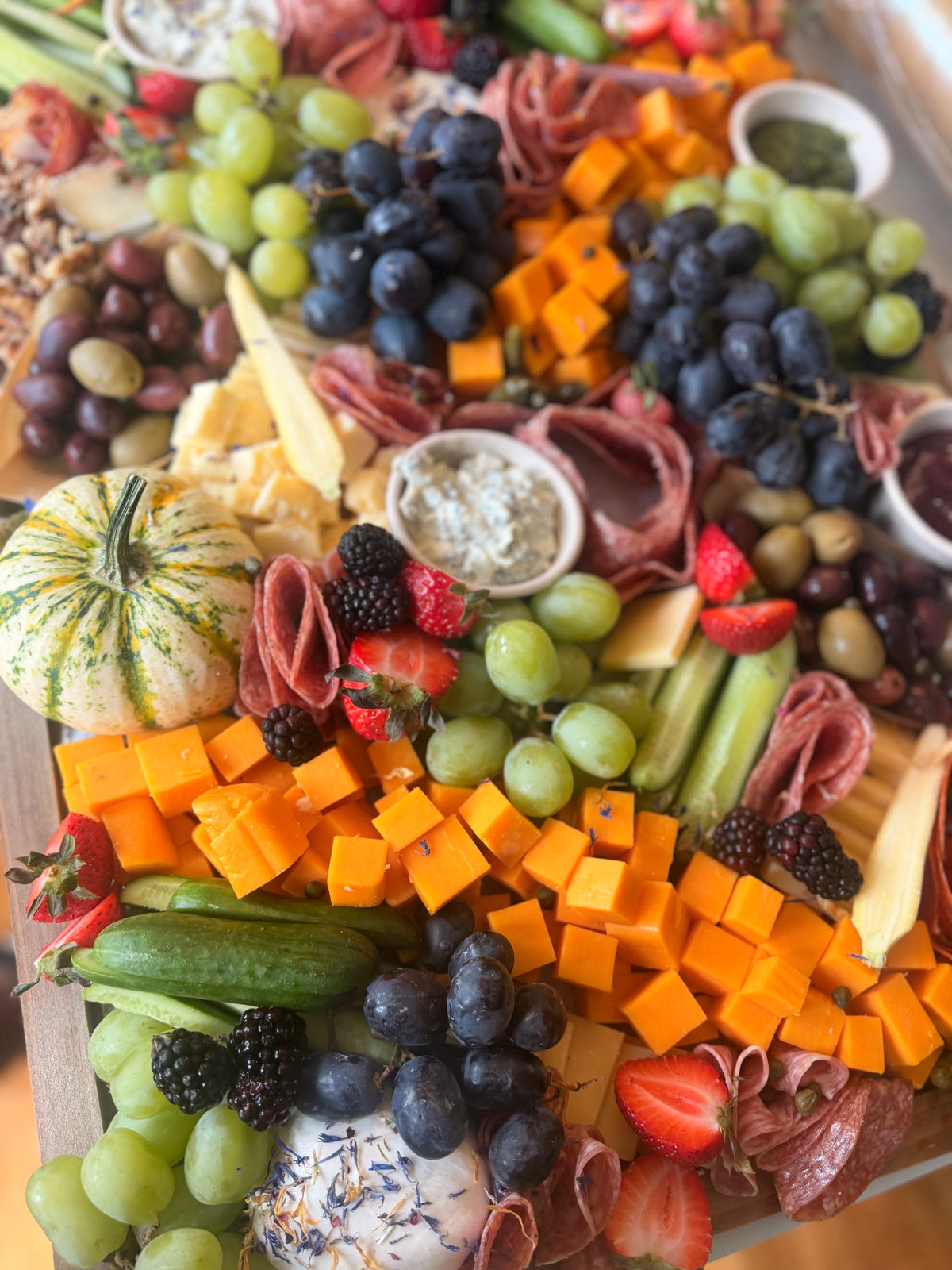 Abundant District Boards grazing table with orchids, cheeses and fresh fruit