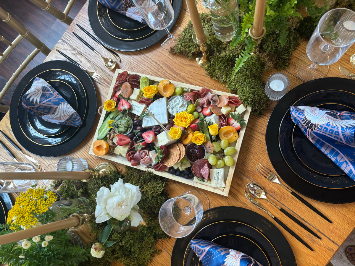 Styled dinner table with a charcuterie board, florals and place settings