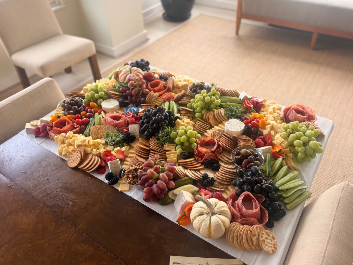 The Federal Reserve Graze flat lay grazing table for 25 guests by District Boards, with salami roses, cheeses, grapes, berries, crackers and pumpkins